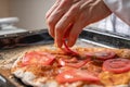 The pizza maker puts tomato slices on the pizza Royalty Free Stock Photo
