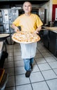 Pizza Maker removes a Fresh Pizza from the oven