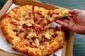 Pizza with meat topping for lunch, served on the table with packaging box.