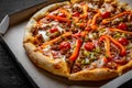 Pizza with Mozzarella cheese, Bolognese sauce, minced meat, pepper, tomato, bacon and vegetables in paper box. Royalty Free Stock Photo