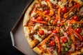 Pizza with Mozzarella cheese, Bolognese sauce, minced meat, pepper, tomato, bacon and vegetables in paper box. Royalty Free Stock Photo