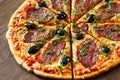 Pizza with Mozzarella cheese, salami, pepper, pepperoni, olives, Spices and Fresh Basil. Italian pizza on wooden background Royalty Free Stock Photo