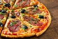 Pizza with Mozzarella cheese, salami, pepper, pepperoni, olives, Spices and Fresh Basil. Italian pizza on wooden background Royalty Free Stock Photo