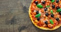 Pizza with Mozzarella cheese, salami, pepper, pepperoni, Tomatoes, olives, Spices and Fresh Basil. Italian pizza on wooden backgro Royalty Free Stock Photo