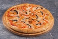 Pizza with mushrooms and tomatoes on a wooden Board on a gray background Royalty Free Stock Photo