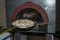 Pizza near the stone stove with fire. Background of a traditional pizzeria restaurant with a fire place