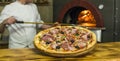 Pizza near the stone stove with fire. Background of a traditional pizzeria restaurant with a fire place