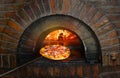 Pizza near the stone stove with fire. Traditional italian pizzeria restaurant.