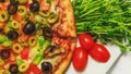 Pizza with olives, pepperoni and red tomatoes, traditional Italian food. Top view of baked vegetable pizza on restaurant table. Royalty Free Stock Photo