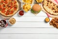 Pizza, onion rings and other fast food on white wooden table, flat lay with space for text Royalty Free Stock Photo