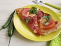 Pizza piece portion sausage fork pepper knife towel tomato on white wooden