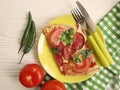 Pizza piece with sausage fork knife on white wooden