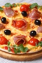 Pizza with prosciutto ham, tomatoes, black olives and arugula