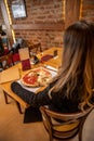 Pizza quattro stagioni with egg served in the restaurant. Woman sitting alone eating pizza in the restaurant Royalty Free Stock Photo