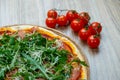 Pizza with red sauce, serrano ham, arugula and shredded mozzarella detail