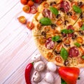 Pizza with Salami Vegetables and Spices on a white wooden background with copy space. Royalty Free Stock Photo