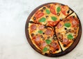 Pizza with sausage, ham, olives and mushrooms on a round wooden cutting board on a light gray background Royalty Free Stock Photo