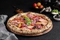 a pizza with sausage, vegetables and tomatoes on a wooden cutting board Royalty Free Stock Photo