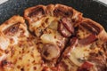 Pizza with sausages and pineapple in a pan.