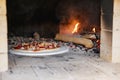 Pizza with sausages and tomatoes in a wood-burning oven against the background of firewood and fire. traditional italian food Royalty Free Stock Photo