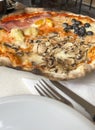 side view pizza with mushroom and olives on table with fork and knife