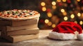 A pizza sitting on a stack of cardboard boxes with a red Santa hat next to it. The background is decorated with Royalty Free Stock Photo