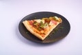 Pizza slice with pepperoni, salami, melted mozzarella cheese, pickles and dill in black plate Royalty Free Stock Photo