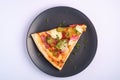 Pizza slice with pepperoni, salami, melted mozzarella cheese, pickles and dill in black plate on white background Royalty Free Stock Photo
