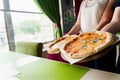 Pizza with tomatoes, mozzarella cheese, basil. Waiter with gloves takes out margarita pizza