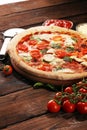 Pizza with tomatoes, mozzarella cheese, black olives and basil. Delicious italian pizza on wooden pizza board Royalty Free Stock Photo