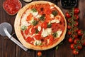 Pizza with tomatoes, mozzarella cheese, black olives and basil. Delicious italian pizza on wooden pizza board Royalty Free Stock Photo