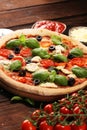 Pizza with tomatoes, mozzarella cheese, black olives and basil. Delicious italian pizza on wooden pizza board Royalty Free Stock Photo