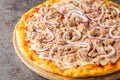 Pizza tonno e cipolla with canned tuna and red onion closeup on the wooden board. Horizontal