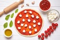 Pizza traditional preparation. Ingredients on the kitchen table: rolled dough with tomatoes sauce Royalty Free Stock Photo