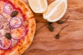 Pizza with tuna, onions, lemon and capers on a wooden dish, tray, background