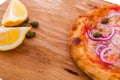 Pizza with tuna, onions, lemon and capers on a wooden dish, tray, background. Horizontal photo