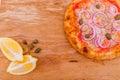 Pizza with tuna, onions, lemon and capers on a wooden dish, tray, background. Horizontal photo