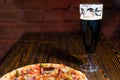 Pizza on wooden table near a glass of dark beer Royalty Free Stock Photo