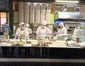 Pizzaiolo puts ingredients in fresh pizza. Female chefs preparing pizza