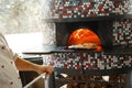 Pizzaola taking out fresh backed pizza out of traditional italian wood-fired oven