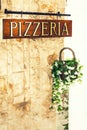 Pizzeria sign on wall with decorative flowerpot