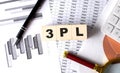 3PL - 3rd Party Logistics text on wooden block on graph background with pen and magnifier