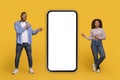 Place For Ad. Cheerful African American Couple Pointing At Big Blank Smartphone Royalty Free Stock Photo