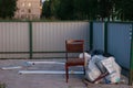 A place for collecting garbage in the yard of several multi-storey buildings. Editorial photo. Someone threw out a chair