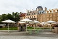 The Place de Paris in summer, with chairs and parasols on its pavement and historic buildings in the background