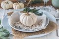 Place setting on a wooden table with white mini pumpkins, sage leaves and natural decoration Royalty Free Stock Photo