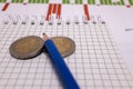 place for text, notebook, graph with pen and euro coins. Close-up of a pen and euro coins on top of a financial graph Royalty Free Stock Photo