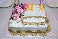 A place to write on the cake. The letters R and V in yellow. Pink flowers on top of the cake. White rectangular cake