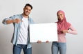 Place For Your Ad. Happy Young Islamic Couple Holding Blank White Placard Royalty Free Stock Photo