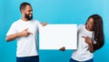 Black couple holding and pointing at blank white advertising board Royalty Free Stock Photo